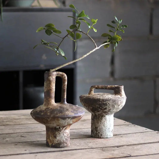 Two rustic ceramic vases with handles on a wooden surface