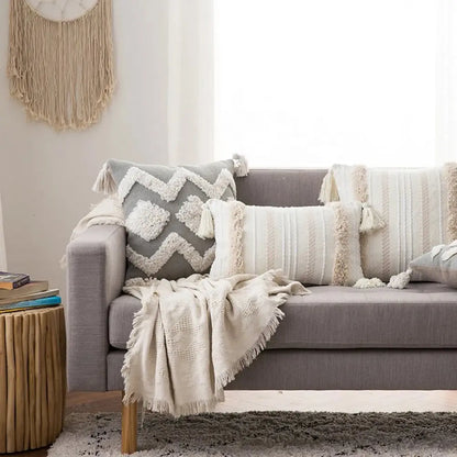 Gray sofa with decorative pillows and a blanket in a living room setting.