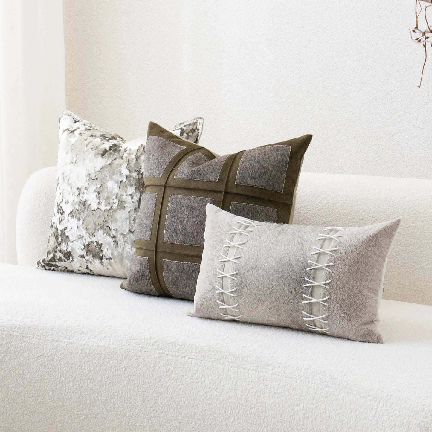 Three decorative pillows on a white sofa with a neutral color scheme.