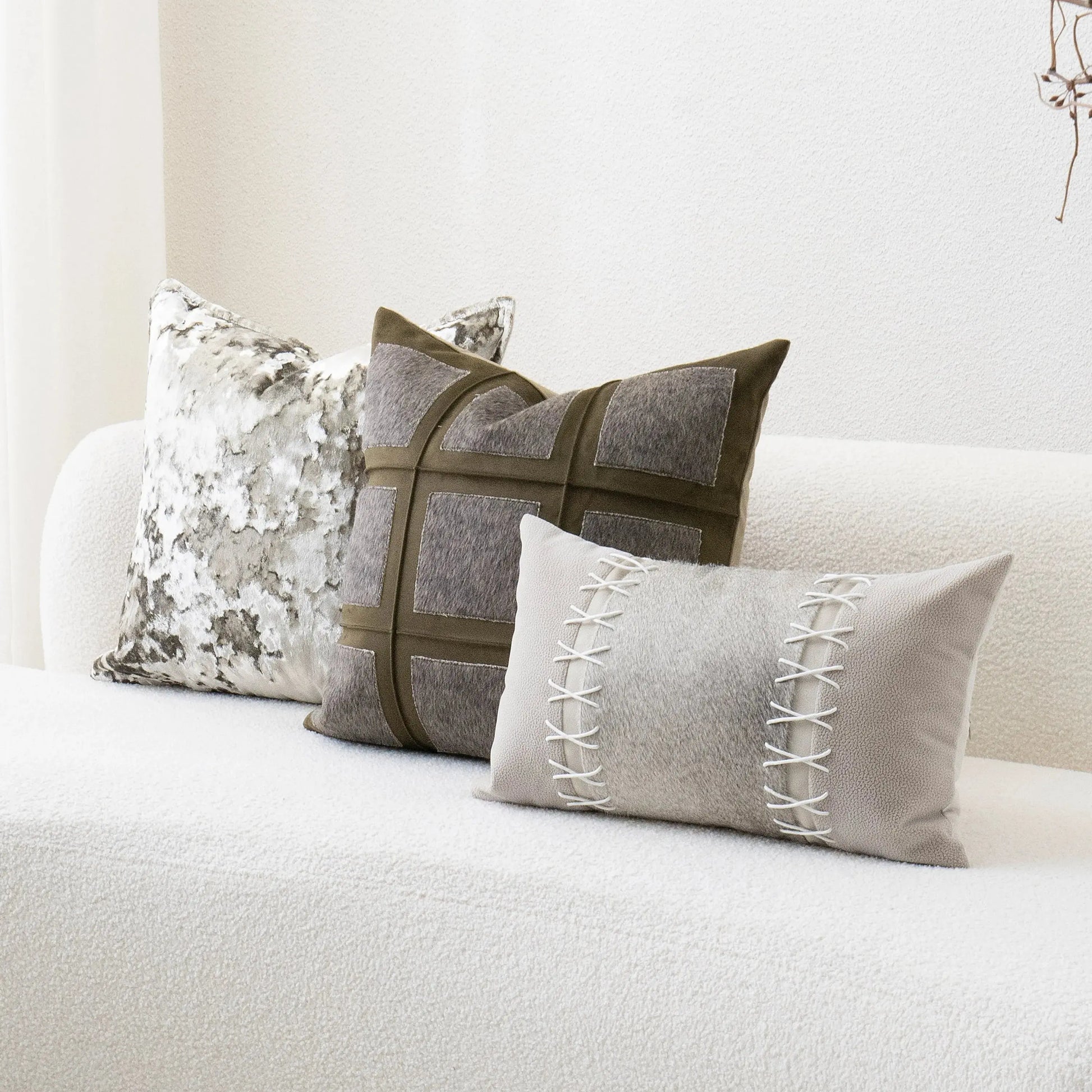 Three decorative pillows on a white sofa with a neutral color scheme.