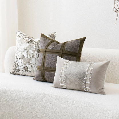 Three decorative pillows on a white sofa with a neutral color scheme.
