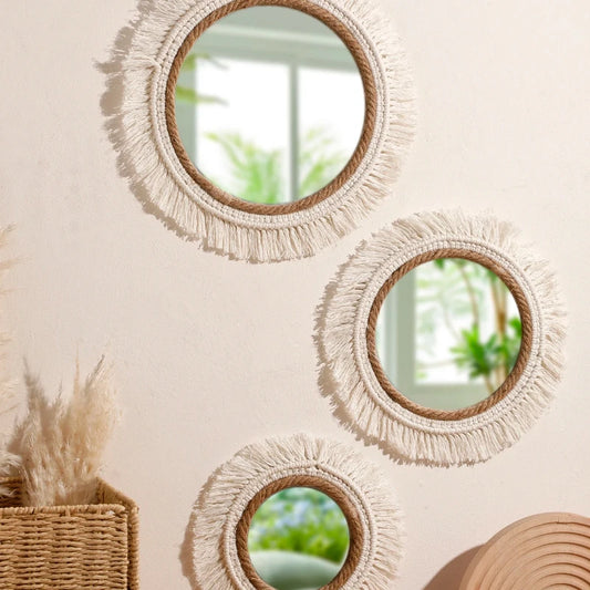Round mirrors with fringe details on a wall, with a natural light setting.