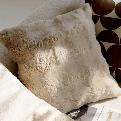 Close-up of fluffy beige pillows on a surface with a patterned background