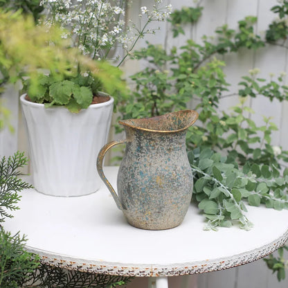 Rustic pitcher on a table with plants in the background