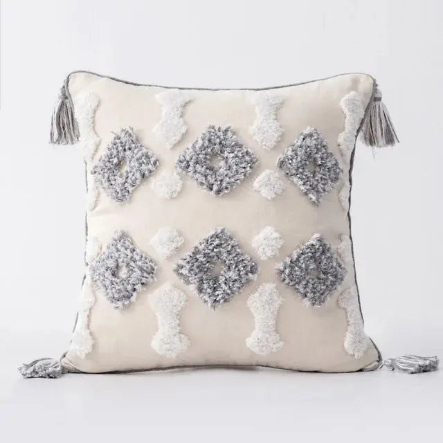 Decorative pillow with geometric patterns and tassels on a light background