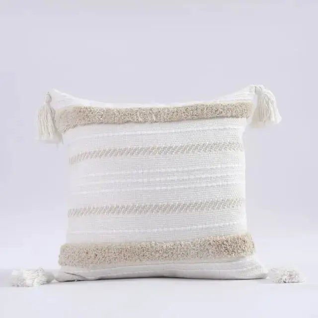 Decorative pillow with striped pattern and tassels on a light gray background