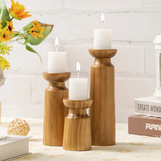Three wooden candle holders with candles on a surface with a blurred background