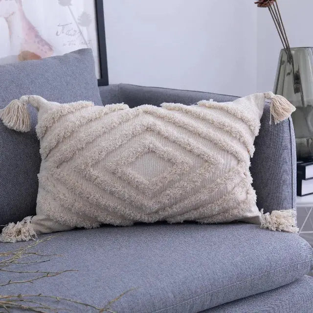 Textured pillow with tassels on a gray sofa in a living room setting.